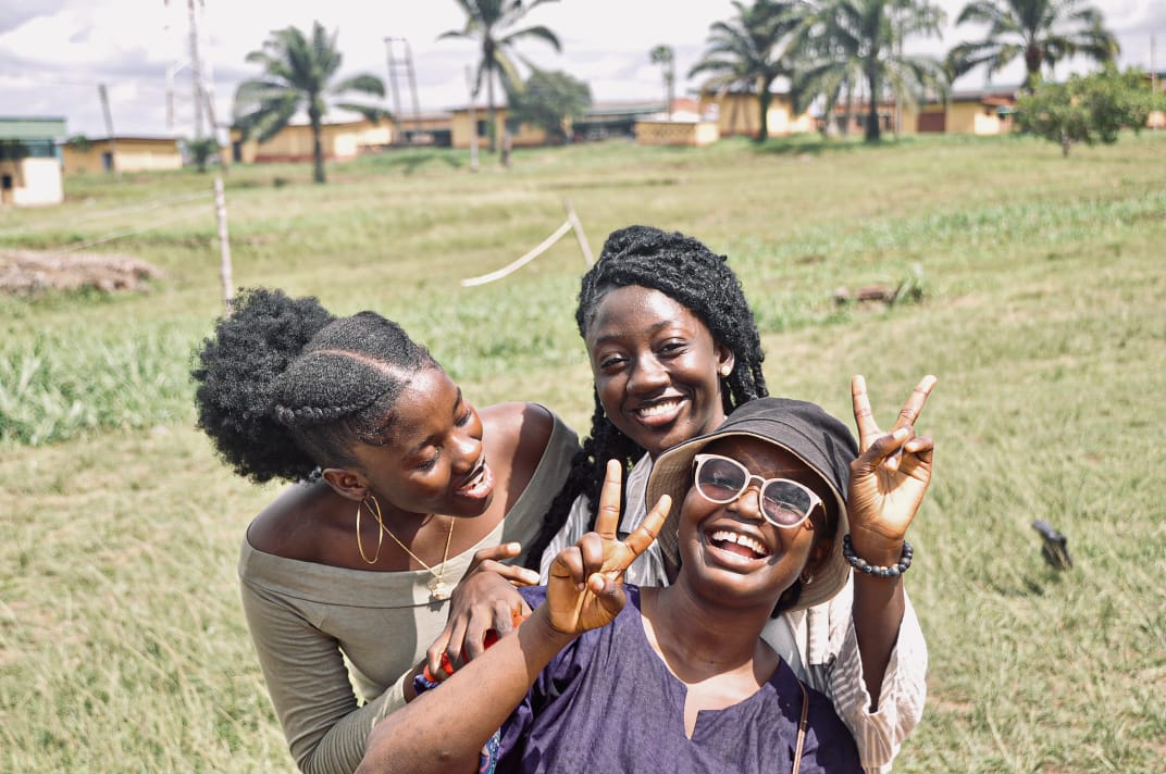 Three friends laughing and posing together on the festival lawn